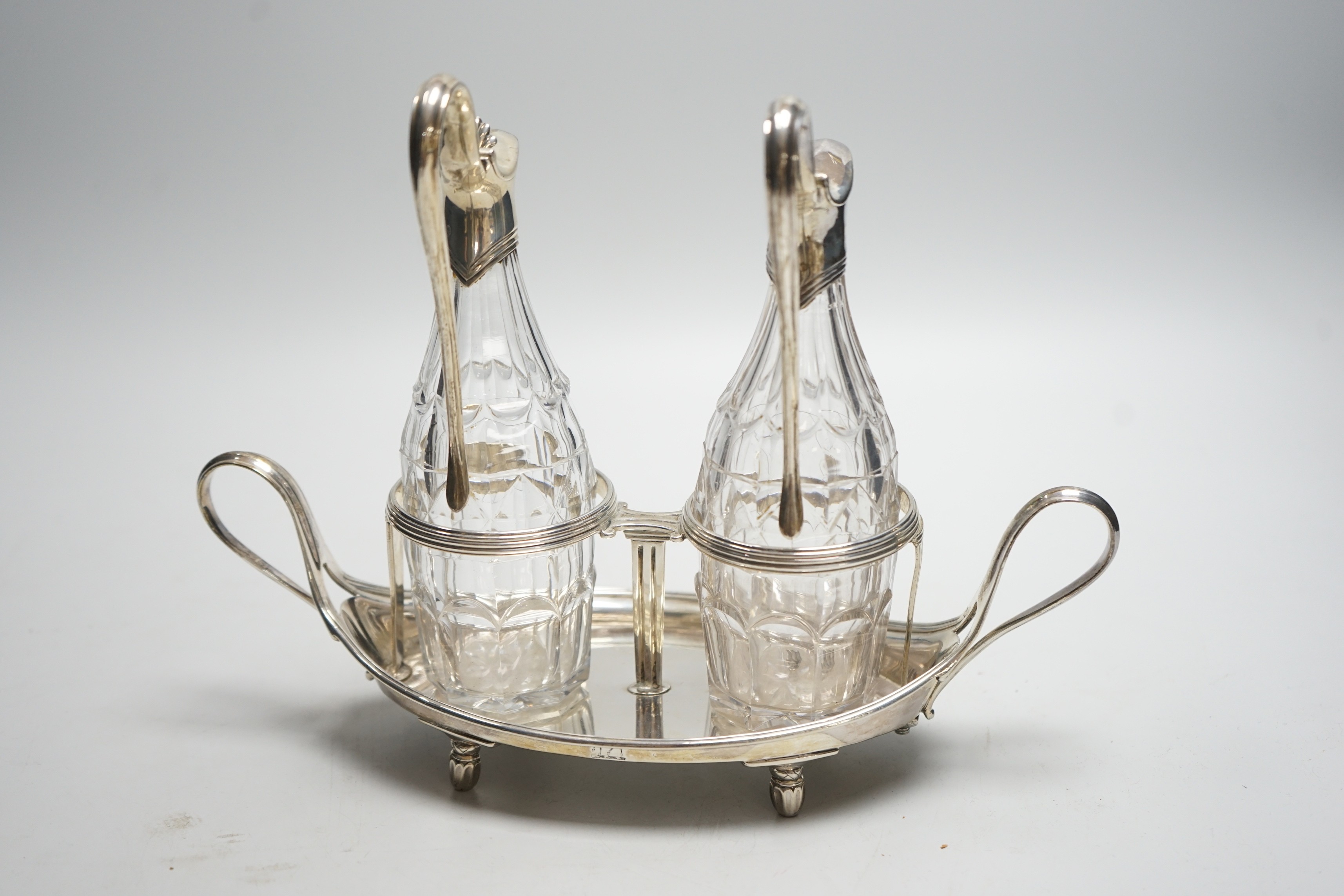 A George III silver navette shaped two handled oil and vinegar stand, with two matching silver mounted cut glass bottles (one thumbpiece missing), John Scofield, London, 1787, length 28cm, stand, 13.7oz.